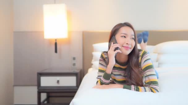 若い幸せなアジアの女性はベッドルームのプライバシーでスマートフォンで話しています スローモーション — ストック動画