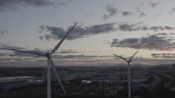 Twee Windgeneratoren Rond Stad Bij Zonsopgang — Stockvideo