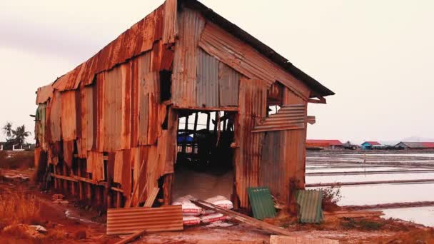カンボジアの有名なカンポット塩田で風が吹くと 錫の壁が剥離して作られた古く風化した塩蔵の家の眺め — ストック動画