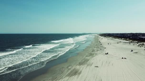 プッシュインドローンは ニュージャージー州ストーンポートのビーチで墜落した白い波を上空から撮影しました ビーチにいる人のカモメやシルエット — ストック動画