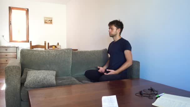 男はソファに集中し 離れて歩くために瞑想し アパートで — ストック動画