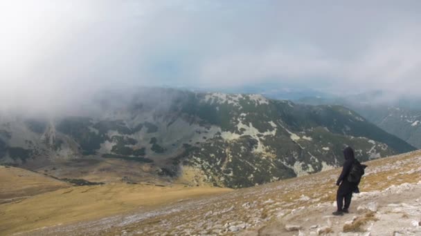 フード付きの男は ブルガリアの霧の中 秋の日に 岩の多い山道の上に立っている ハンドヘルド スローモーションビュー — ストック動画