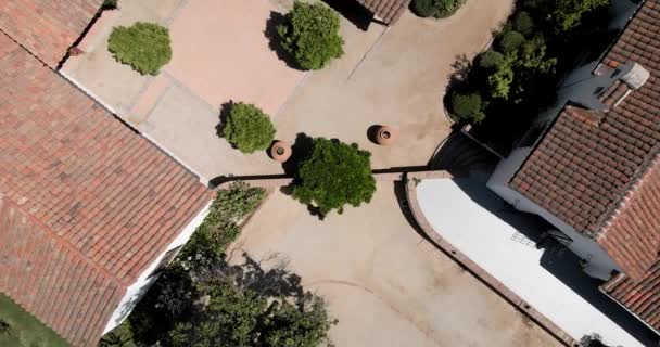 植民地時代の建物の木の下を通り過ぎる黒いドレスを着た者の頭上の眺め — ストック動画