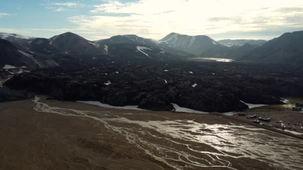 冰岛兰德尔加尔市彩虹山脉中一个巨大的黑色岩浆场前面的河床和一个露营地 — 图库视频影像