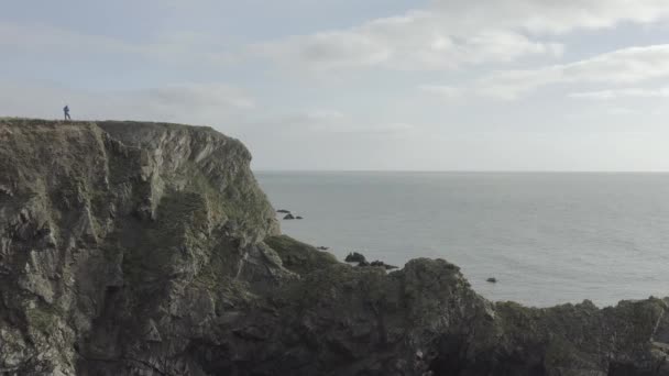 海を見下ろす険しい岩の崖の上の無人機パイロットの静的なショット — ストック動画