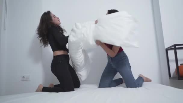 Two Women Laughing While Pillow Fighting Bed Medium Shot — Stock Video