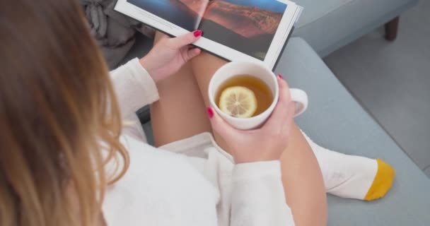 Young Caucasian Woman Sitting Reading Travel Magazine While Drinking Tea — Stock Video