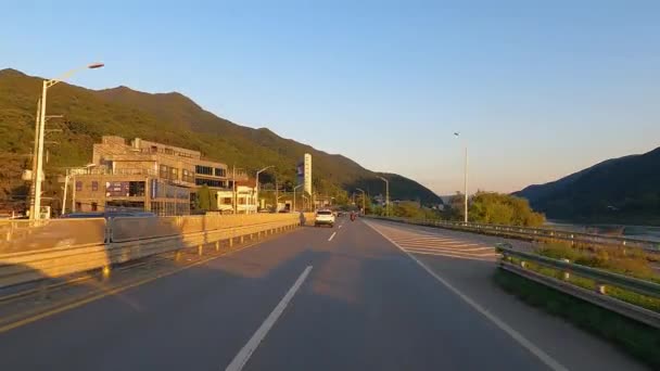 朝鮮の田舎の日没時に川によって陽平ダムとパルダンダムへの道路上の山を通って運転運転運転運転のPov — ストック動画