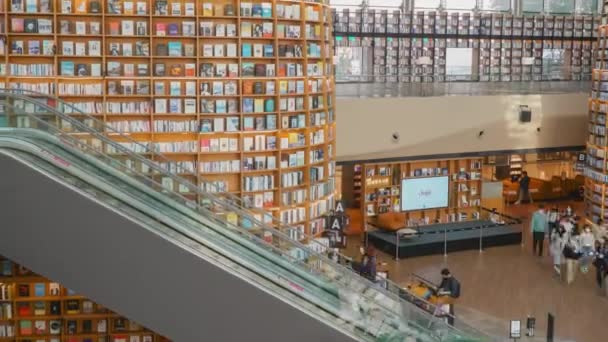 Escalator a Starfield könyvtárban. Koreai látogatók mozognak emeletek között a közkönyvtár hatalmas könyvespolcok - zoom out time lapse