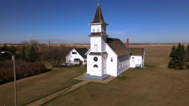 加拿大艾伯塔省圣博尼法斯天主教堂周围的低空轨道 在20世纪初 一个白色的废弃乡村小礼拜堂的4K段录像是由木头制成的 旗杆的文物建筑 — 图库视频影像