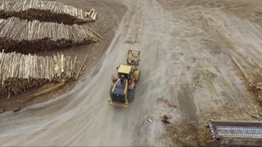 Makinelerin endüstriyel odun öğütücüsüne kütük ekleyip hamuru için odun parçaları ve kâğıt parçalarını oluşturduğu tepeden drone görüntüsü.