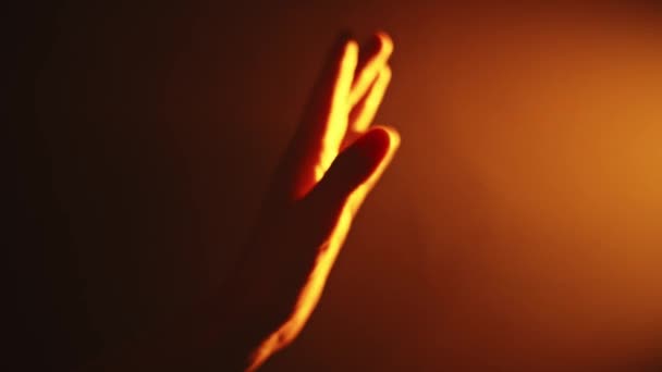Χέρι Κινείται Μπροστά Από Μια Φωτεινή Πορτοκαλί Πηγή Φωτός Ένα — Αρχείο Βίντεο