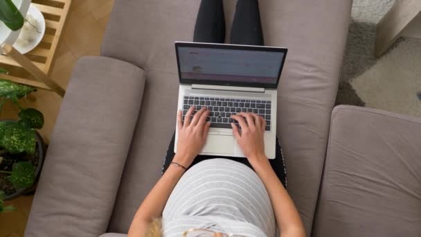 Terhes nő pihentető kanapén ír e-maileket a laptop, felülről lefelé