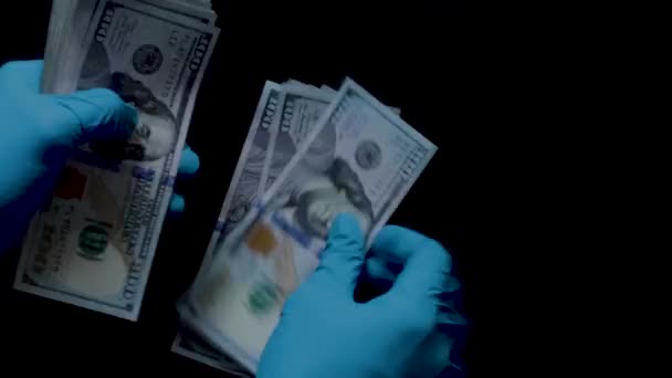 4K 24fps hands counting a fat stack of one hundred dollar bills onto a black background ideal for screen layering.  Nitrile gloved.
