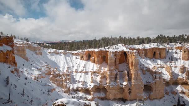 タイムラプス ブライスキャニオン国立公園 ユタ州晴れた冬の日に米国 雪は移動中の雲の下でレッドロック砂岩の崖や洞窟をキャップ — ストック動画