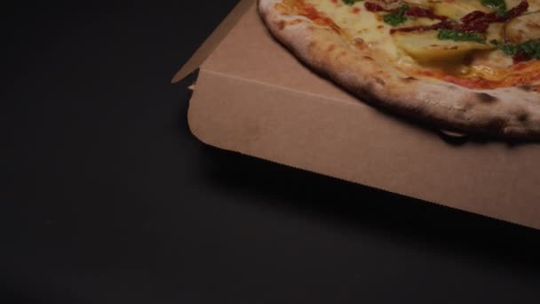Zblízka pohled na lahodnou pizzu na vrcholu krabice na pizzu v černém pozadí.