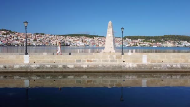 希腊克法隆尼亚首府阿尔戈斯托利市最有名的方尖碑前走过的女人 — 图库视频影像