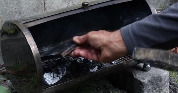パン生地のベーキングトレイを屋外の小さな木炭燃焼オーブンに置く — ストック動画