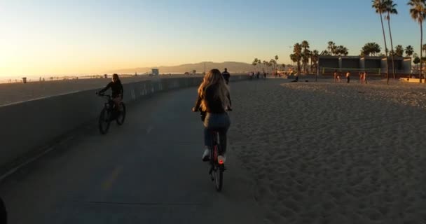 美しい夕日の間のヴェネツィアのビーチ自転車道の女性 — ストック動画