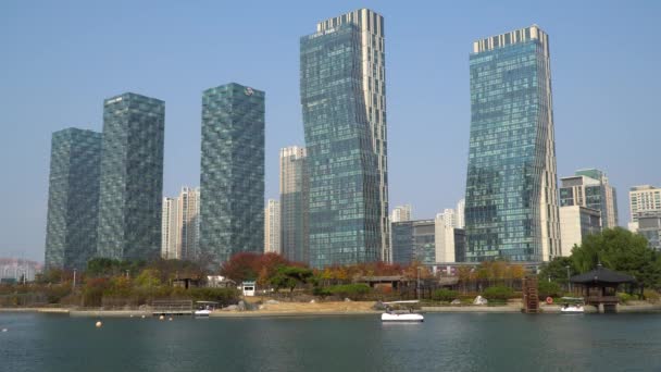 松島中央公園からの高層マンション高層マンションの都市景観と青い空を背景に湖で家族経営の舟遊びをする人々 撮影を確立 — ストック動画