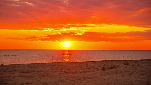 海の上にオレンジ色の空で穏やかな日の出の時間の経過ショット 砂のビーチで朝の空を飛ぶ雲と絵のような風景 — ストック動画