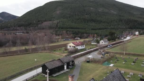 ノルウェーの内陸郡にあるトムストーンに囲まれたヒーディッド スターブ教会のある森の山 空中プルバック — ストック動画