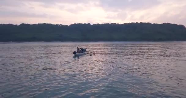 南ゴアの日の出の間に熱帯の海で伝統的なアウトリガー木製のボートを持つ男性 インド — ストック動画