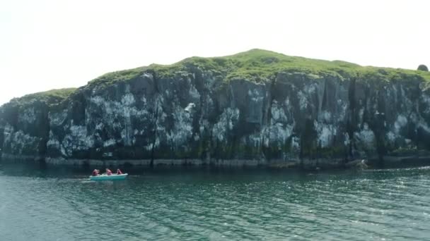 アイスランドのBreidafjordur Bay Flatey島の近くにボート観光客とロッキークリフ 空中ドローン軌道 — ストック動画