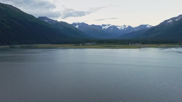 アラスカの冷たい平らな湖の水面の上を飛ぶドローン 晴れた日の山の風景 — ストック動画