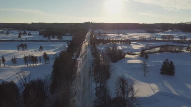 冬の田園風景の中でゴルフコースを分ける道路の空中フライオーバー — ストック動画