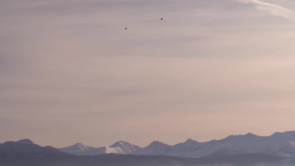 夕阳西下 两个热气球在雪山上空高高飘扬 — 图库视频影像