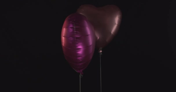 Srdce tvarované fólie balónky v černém pozadí, dekorace na Valentýna. - detailní
