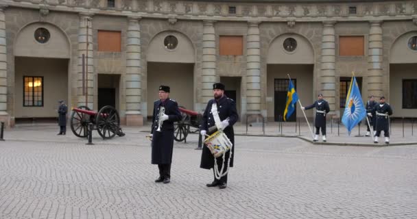 ガードは スウェーデン ストックホルムのGamla Stanの王宮の外コートヤードで警備員を変更する際にドラムとバギーコールを再生します — ストック動画