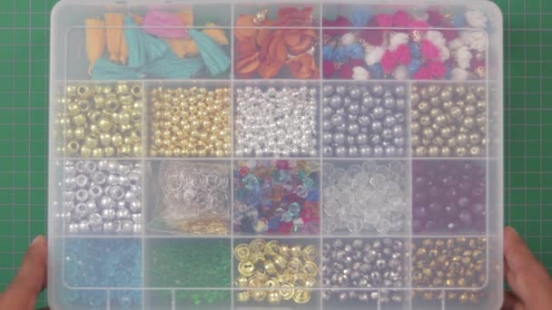 korálky, kameny a šperky v plastové krabici.