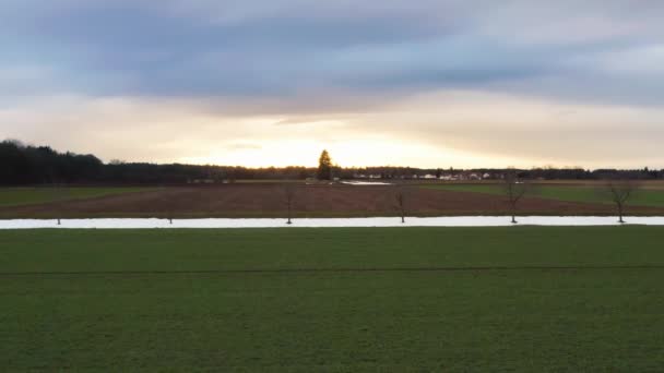 灿烂的太阳正在下山 在光秃秃的田野里的最后一片雪地上飞舞 — 图库视频影像