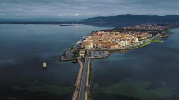 イタリアのトスカーナ州のモンテ アルゼンティアリオとマレマ自然公園の近くにある旧島の町Orbetelloへのラグーンを渡る橋の道路上の車の交通 水の反射 空中ドローン飛行 — ストック動画