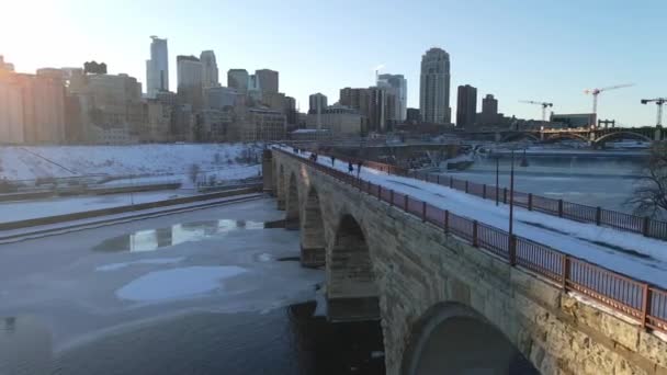 ミネアポリスの冬の午後にミシシッピ川を渡る石造りのアーチ橋の人々の空中ビュー — ストック動画