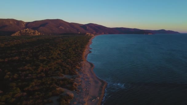 イタリアのトスカーナ州にあるマレーマ国立公園 Uhd遠くの島と青空と夕方の空と水と夕日で松の木の森とビーチ海辺の海の海岸の空中ドローン映像 — ストック動画