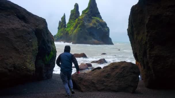 冰岛里尼斯法加拉黑沙海滩穿越巨石阵的人背景下的里尼斯兰德加玄武岩形成 — 图库视频影像