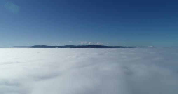 平稳地接近下方低云上方的遥远滚动的小山 — 图库视频影像