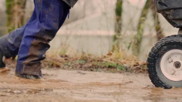 Onherkenbaar Persoon Duwt Een Kruiwagen Door Modder Water Buitenwerkers Met — Stockvideo