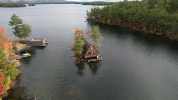 岛上的湖畔小屋 美国新罕布什尔州温尼皮索基湖五彩缤纷的秋天风景中 岛上房屋的空中景观 环绕无人驾驶飞机射击 — 图库视频影像