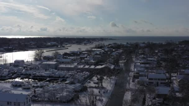 在最近的降雪后的一个晴朗的日子里 纽约湾海岸上空的无人驾驶飞机图像 摄像机在住宅区上空朝水的方向旋转 可以看到地平线 — 图库视频影像