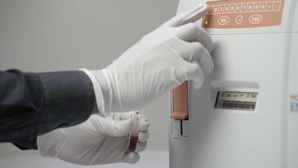 医学技师的手在可处置的手套中保存血液样本 推动电解质分析仪的钮扣 慢动作 — 图库视频影像