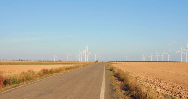 夏天在西班牙阿拉贡 一条空旷的柏油路穿过有风力涡轮机的田野 Pan Right Shot — 图库视频影像