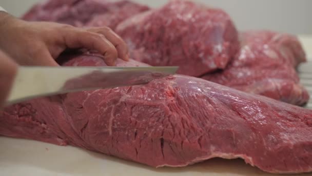 男性の肉屋はおいしい生の牛の肉をナイフで半分に切って閉じます — ストック動画