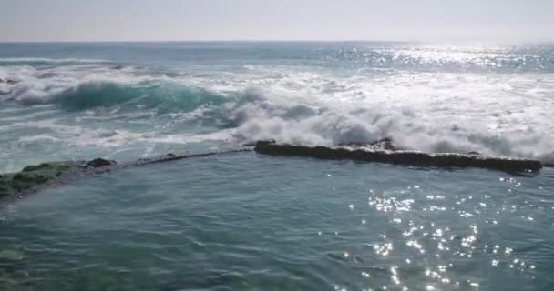 カメラがカリフォルニア州ラグナビーチのビクトリアビーチ海賊タワーを明らかにするにつれて 太平洋の波は海岸に衝突します — ストック動画