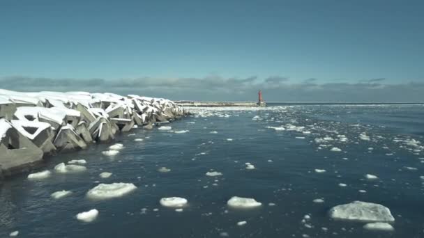 北海道 近江の防波堤横の空中流氷を背景に赤い灯台が広がる ドリー フォワード — ストック動画