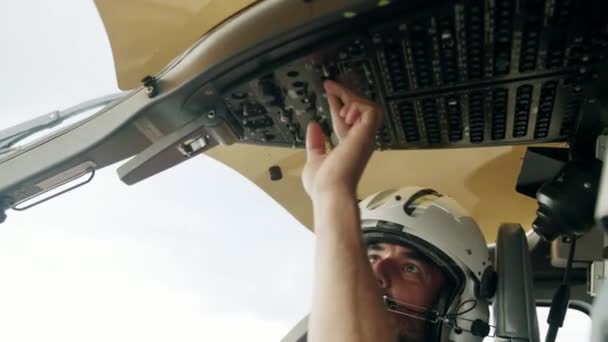 ヘリコプターコックピットのオーバーヘッドコントロールパネルのノブを起動し オンにパイロットのクローズアップスローモーションショット — ストック動画