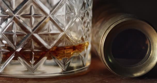 一杯几乎是空的波旁威士忌坐在一个桌面上 旁边是一个间谍杯 镜片深处反射的火光 — 图库视频影像